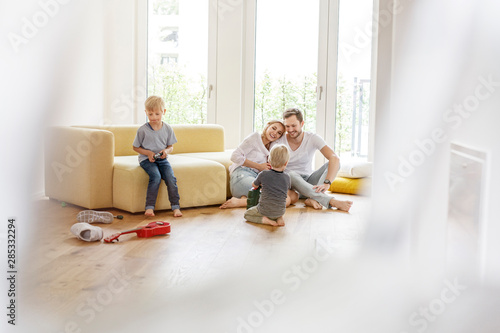Happy family with two sons playing in living room of their new home