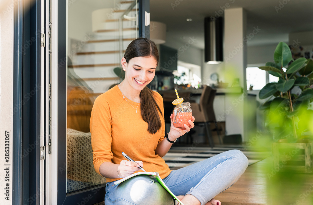 Young woman sitting with healthy drink and notebook at terrace door Young woman sitting with healthy drink and notebook at terrace door