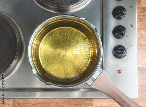 Oil in a pot situated over the stove. View from above