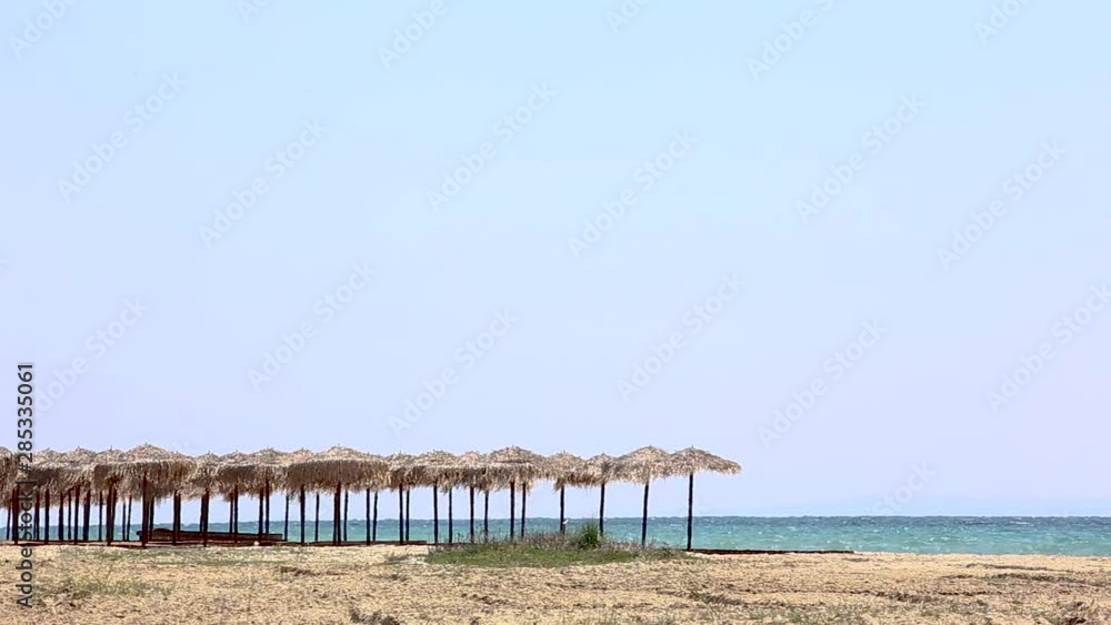 Wicker beach umbrellas by the sea, beach without people, Greece Wicker beach umbrellas by the sea, beach without people, Greece
