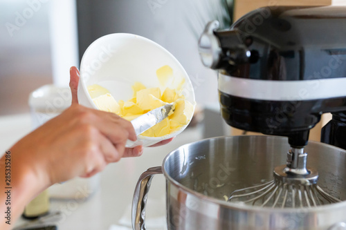 adding butter into bowl of stand mixer, mixing buttercream icing