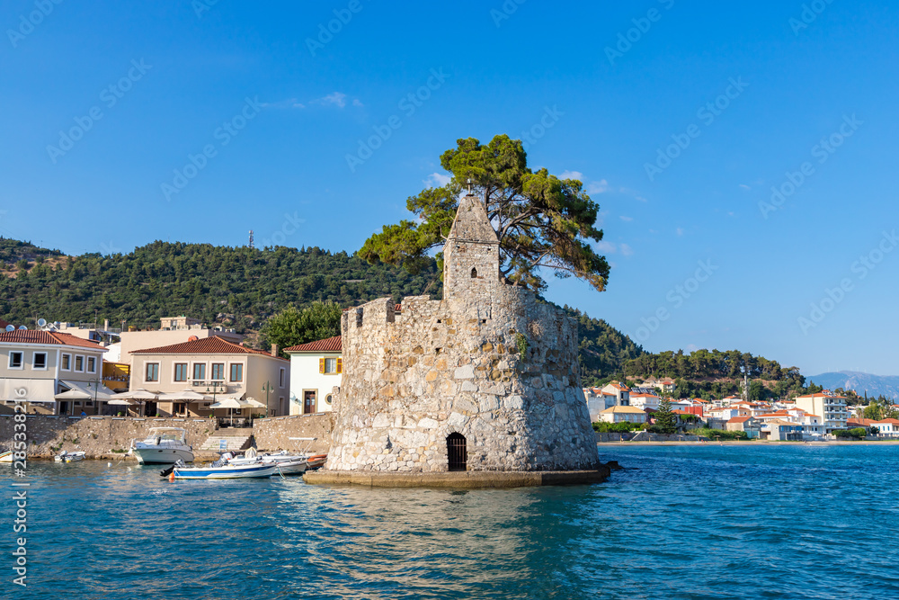 View of the port of Nafpaktos with the famous statue and a greek flag. Greece