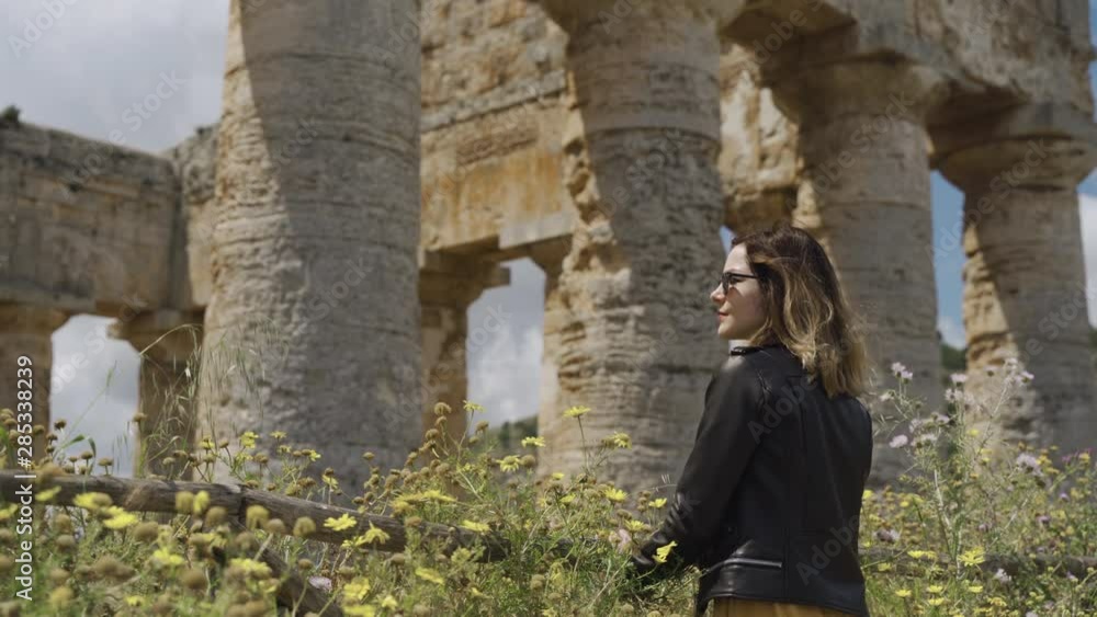 Woman standing by ancient ruins temple of Segesta in Sicily Woman standing by ancient ruins temple of Segesta in Sicily