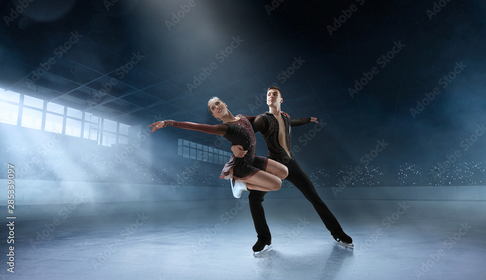 Figure skating couple in professional ice arena.