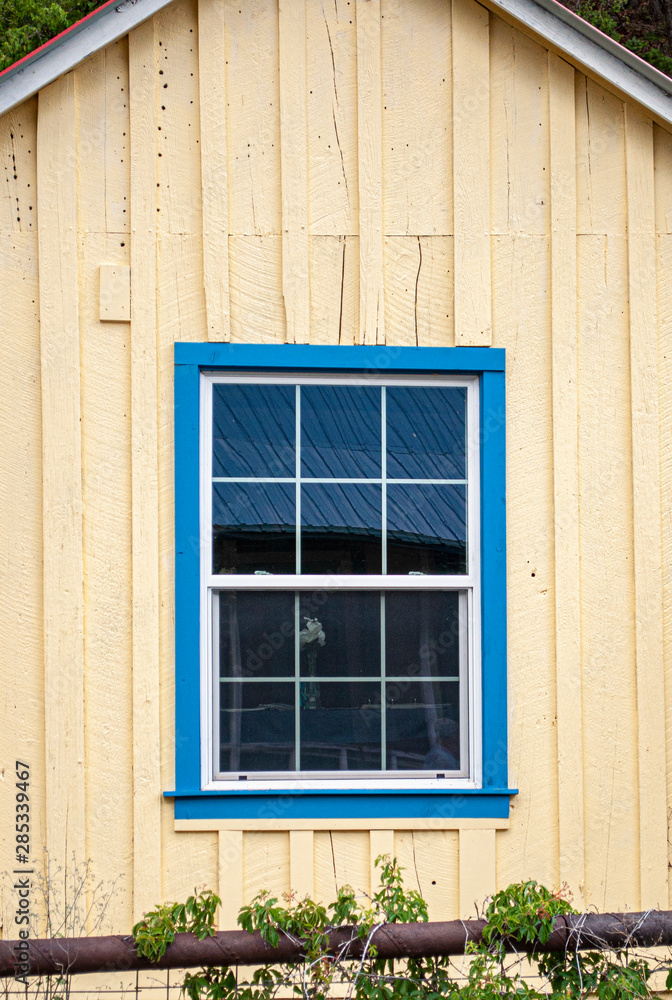 Old house with yellow wall with blue window trim Old house with yellow wall with blue window trim