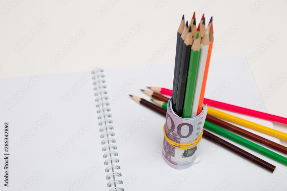 molen Roeispaan slijm colored pencils wrapped in euro note on a white notebook on a white table  bright copy space Stock Photo | Adobe Stock