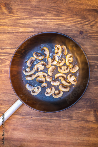 chopped mushrooms fried champignon in a skillet in oil. frying pan heat