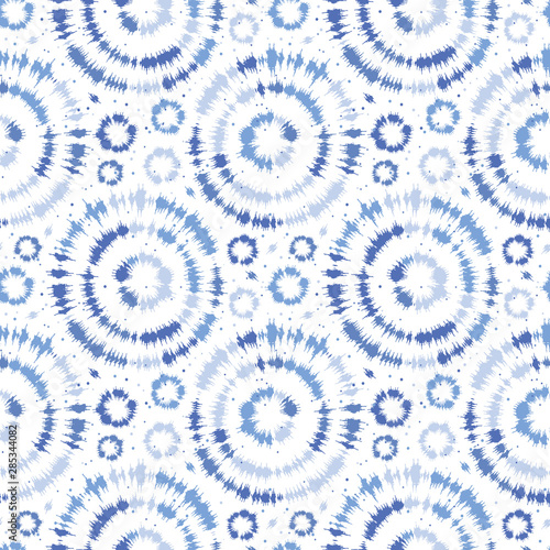 Indigo blue shibori tie dye sunburst circle background. Seamless pattern on white background. Japanese style batik textile. Variegated for summer fashion swatch.