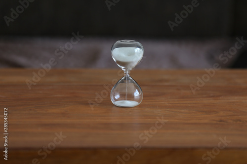 Time. Glass hourglass stands on the table.