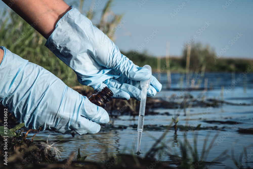 Water pollution concept. Woman scientist takes a water sample from polluted pond. - obrazy, fototapety, plakaty 