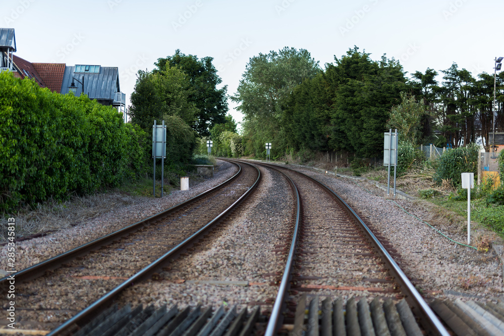 An empty train track, there are 2 tracks leading to a point on the horizon in rural countryside An empty train track, there are 2 tracks leading to a point on the horizon in rural countryside