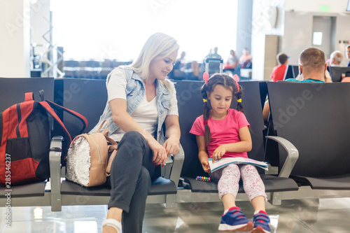 Mom and child are waiting for their plane at the airport. Passengers are waiting for their transport in the station