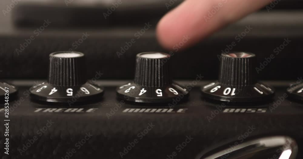 Guitar Player Adjusting Treble Middle And Bass Knobs On Guitar Amp