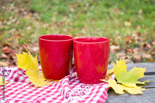 Two red cups on an autumn background