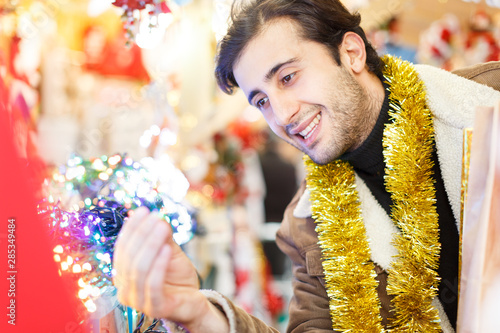 Young man with garland buying decoration at Christmas Fair outside