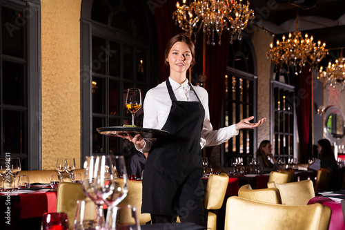 Female waiter standing with serving tray, recommending dishes in restaurant