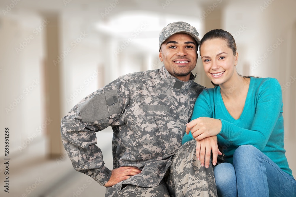 Fototapeta premium Smiling soldier with his wife standing against background