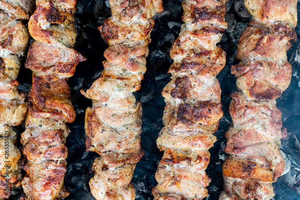 Frying pork on a skewer over a brazier. Turning meat over coals. Appetizing shish kebab.