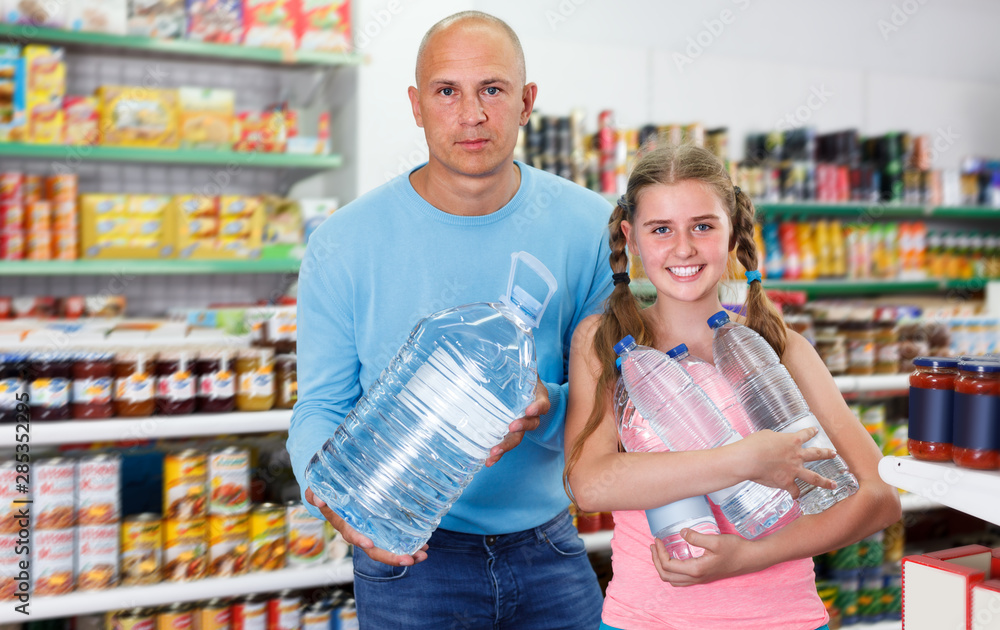 family of father and tween daughter buying still water in supermarket