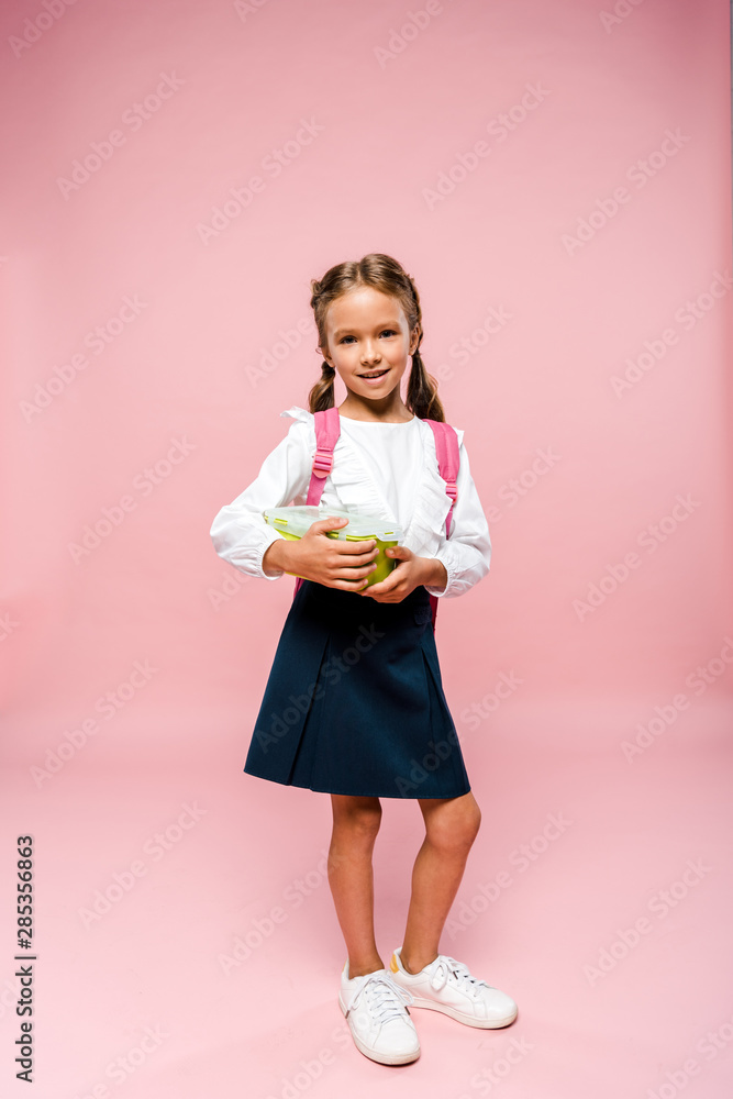 happy kid holding lunch box and standing on pink happy kid holding lunch box and standing on pink