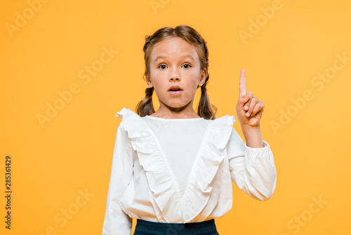 surprised schoolkid having idea isolated on orange