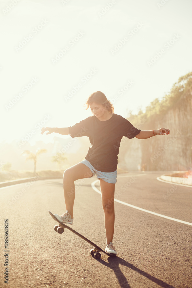 Beautiful sexy young girl in short shorts walking with longboard in sunny weather. Leisure. Healthy lifestyle. Extreme sports. Fashion look, outdoor hipster portrait, Bali, sneakers,hipster,sunset