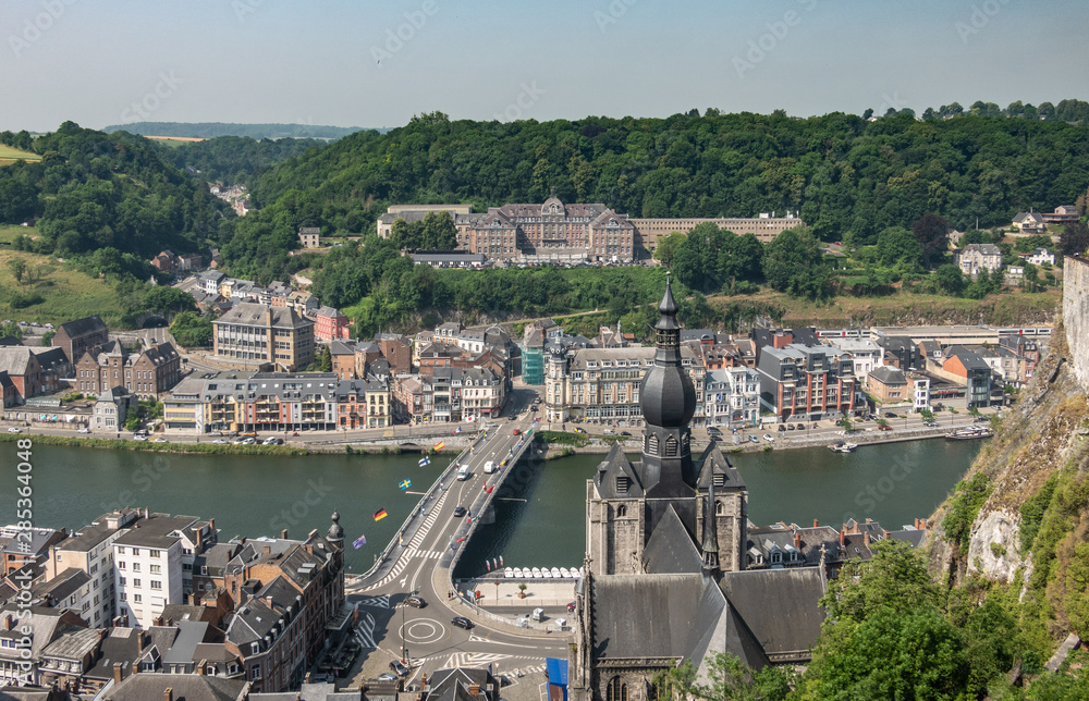 Dinant, Belgium - June 26, 2019: Seen from Citadelle. Large building on top is College Notre Dame de Bellevue, school system from primary to high school. Forests in back. City, river and church - obrazy, fototapety, plakaty 