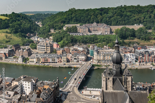 Fototapeta Naklejka Na Ścianę i Meble -  Dinant, Belgium - June 26, 2019: Seen from Citadelle. Large building on top is College Notre Dame de Bellevue, school system from primary to high school. Forests in back. City, river and church