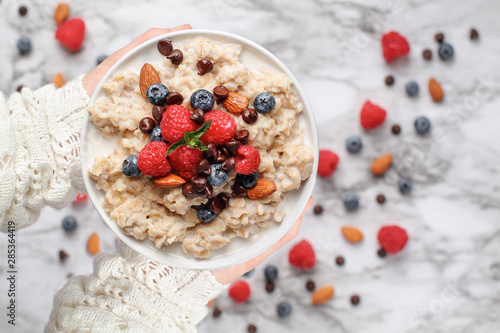 Canvas Print Healthy oatmeal served with berries, chocolate chips, almonds and honey