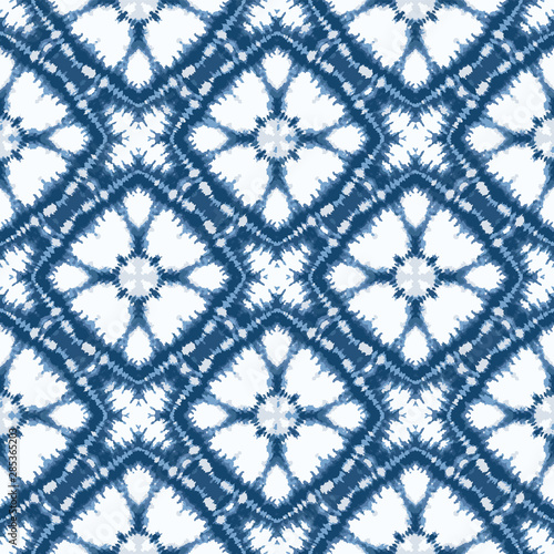 Indigo blue shibori tie dye sunburst flower circle background. Seamless pattern on white background. Japanese style batik floral textile. Variegated for summer fashion swatch.