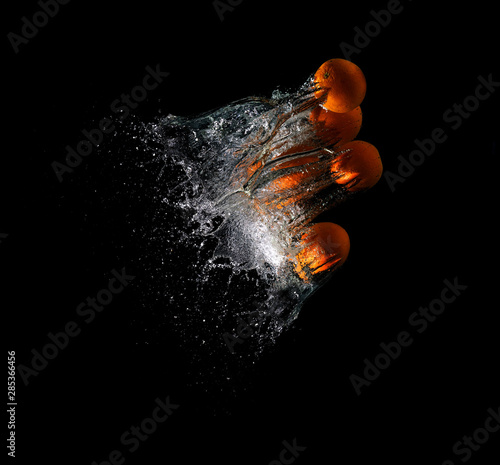 fresh oranges falling in water on a dark background