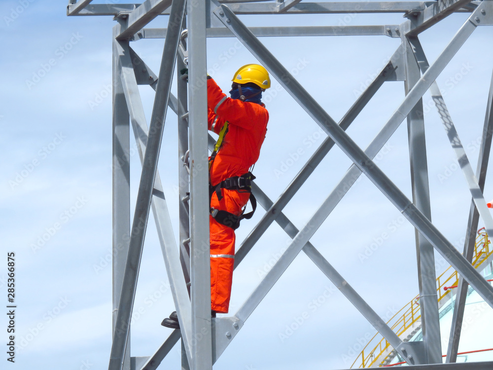 Man Working on the Working at height. Professional industrial climber in helmet and uniform works at height. Risky extreme job. Industrial climbing at construction site.   