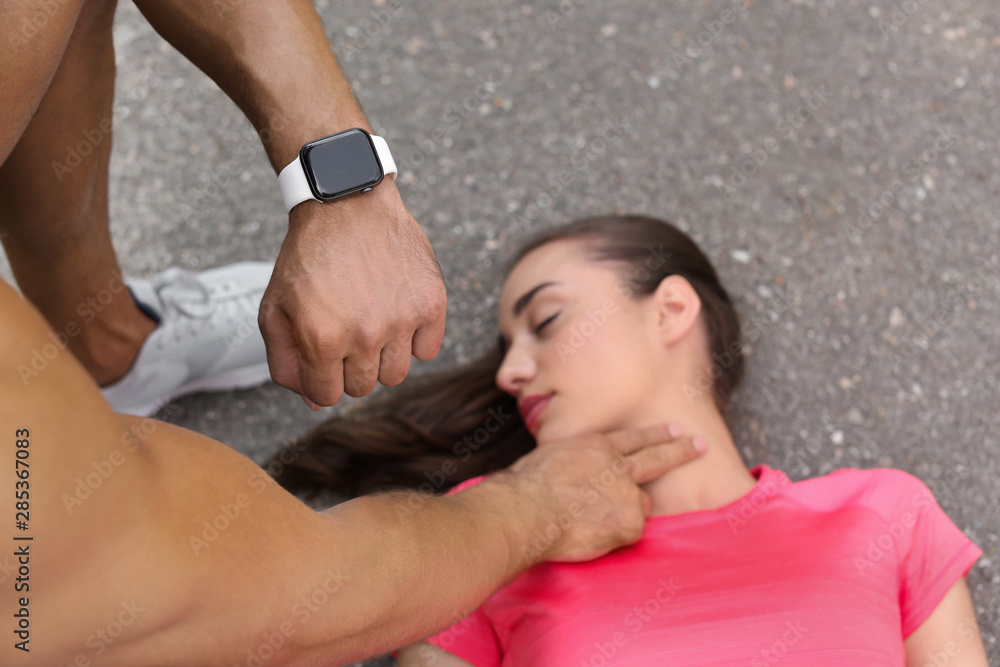 Young man checking pulse of unconscious woman on street Young man checking pulse of unconscious woman on street