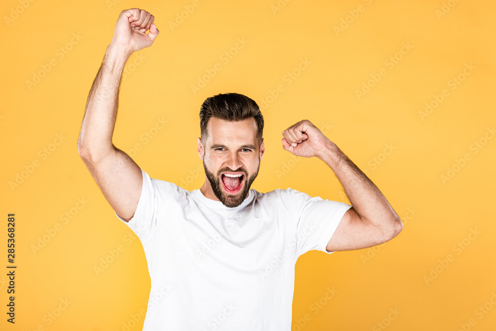 Fototapeta premium happy handsome man in white t-shirt showing yes gesture isolated on yellow