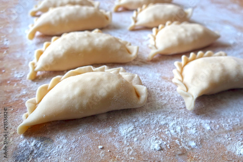 dumplings close-up, filled with cottage cheese dumplings or pies, traditional cuisine, pastries, sprinkled with flour.