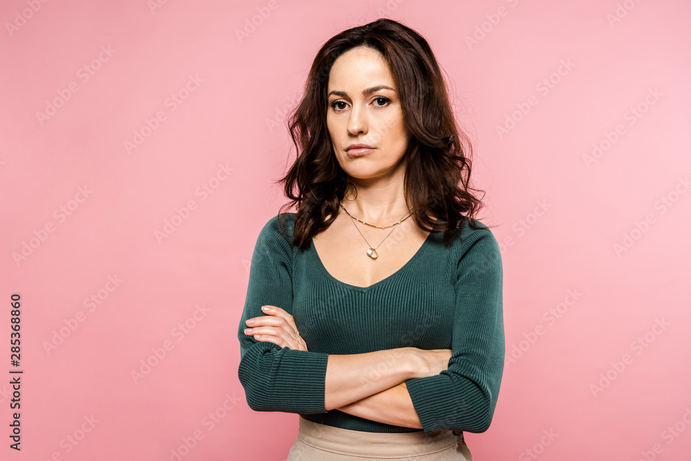 upset woman standing with crossed arms isolated on pink upset woman standing with crossed arms isolated on pink