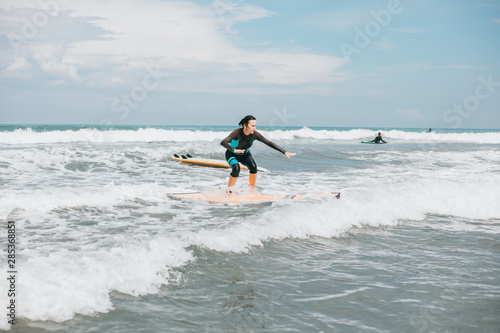 Surfer girl walking with board on the sandy beach. Surfer female.Beautiful young woman at the beach. water sports. Healthy Active Lifestyle. Surfing. Summer Vacation. Extreme Sport. Tattoo woman, Bali