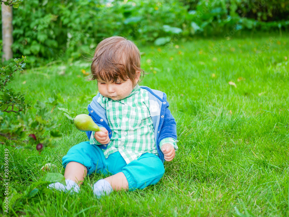 Baby and nutrition concept. Healthy Street Fun for Kids. Kid eats a pear on the grass. natural food Baby and nutrition concept. Healthy Street Fun for Kids. Kid eats a pear on the grass. natural food
