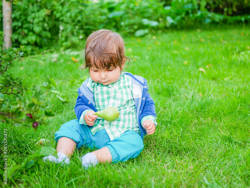 Baby and nutrition concept. Healthy Street Fun for Kids. Kid eats a pear on the grass. natural food Baby and nutrition concept. Healthy Street Fun for Kids. Kid eats a pear on the grass. natural food