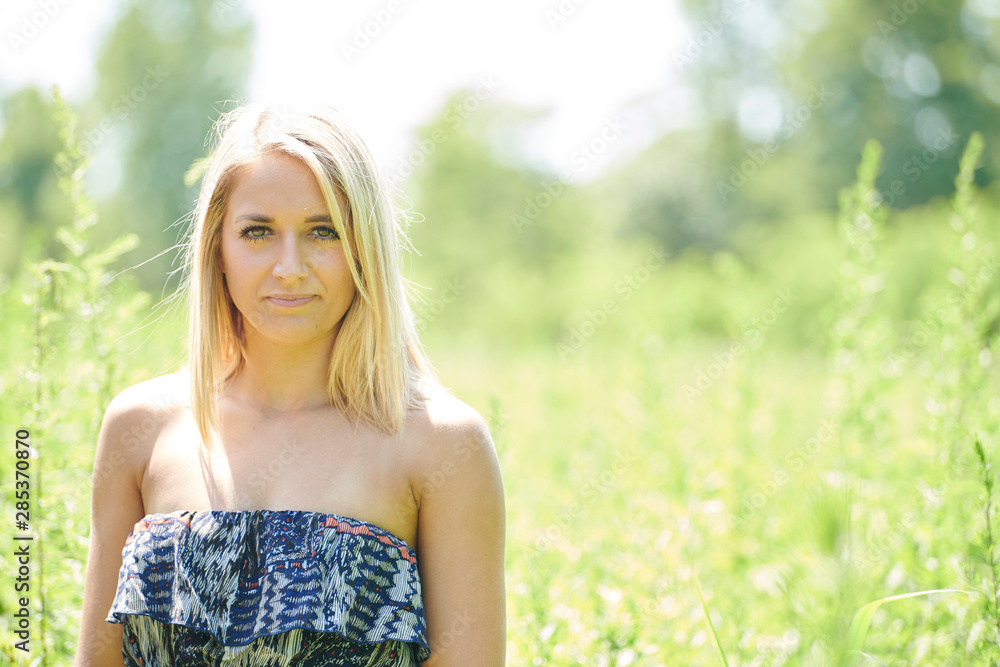 Beautiful young blonde woman poses outside in off the shoulder sundress - posing near tall grass in open field Beautiful young blonde woman poses outside in off the shoulder sundress - posing near tall grass in open field
