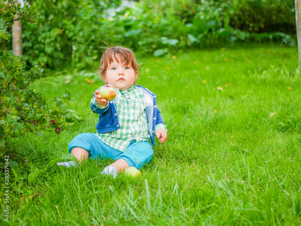 Baby and nutrition concept. Healthy Street Fun for Kids. Kid eats a pear on the grass. natural food Baby and nutrition concept. Healthy Street Fun for Kids. Kid eats a pear on the grass. natural food