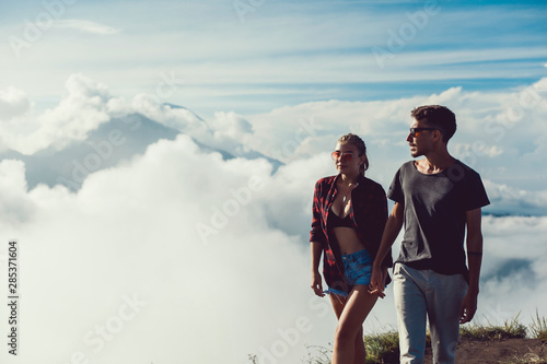 Hikers with backpacks relaxing on top of a hill and enjoying view of sunset in ocean. Island Lombok, Indonesia. Traveling along mountains and coast, freedom and active lifestyle concept