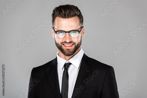 happy successful businessman in black suit and glasses isolated on grey