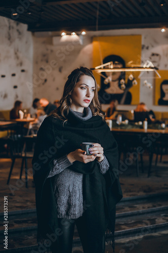 A beautiful girl in a beige jacket drinks coffee from a glass talking on the phone, wearing sunglasses works in the office in the business center, the manager, the employee of the company, happy face