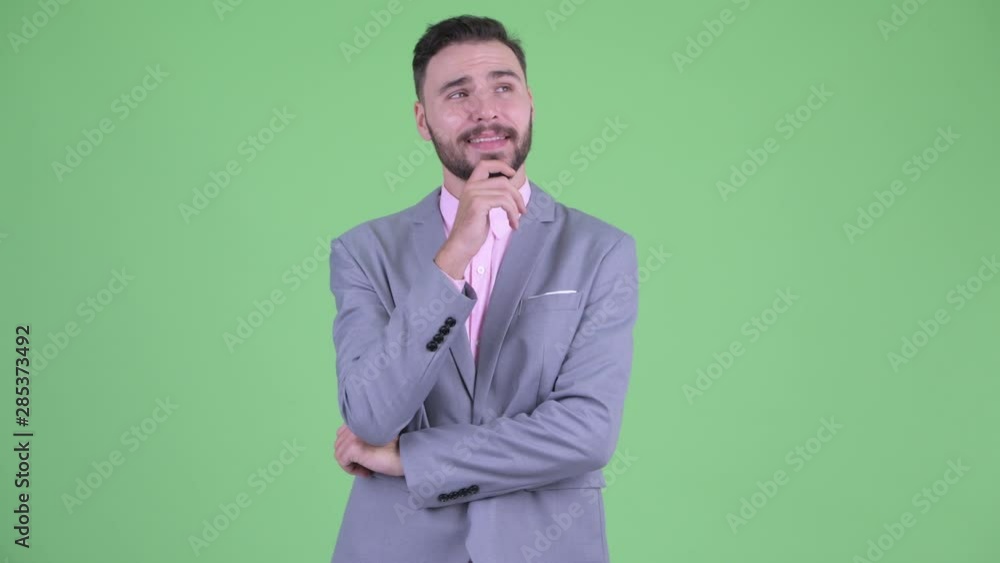 Happy young bearded businessman thinking and looking up Happy young bearded businessman thinking and looking up