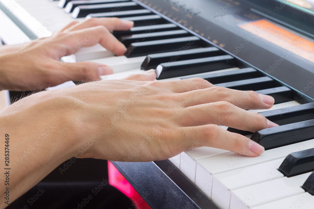 Obraz premium Piano Player Hand on Electric Piano in Crosswise View