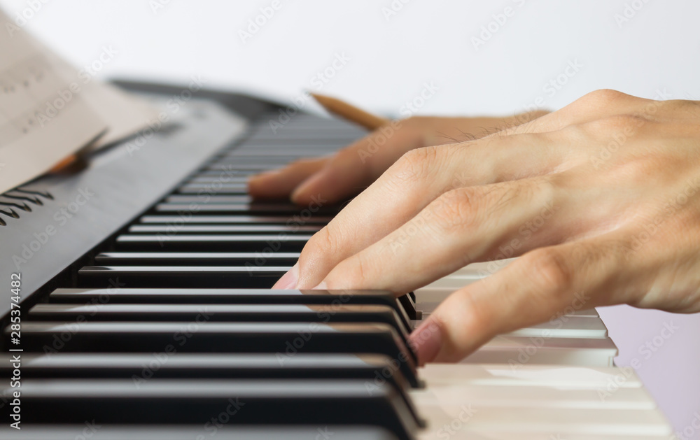 Obraz premium Piano Player Hand on Electric Piano with Sheet music