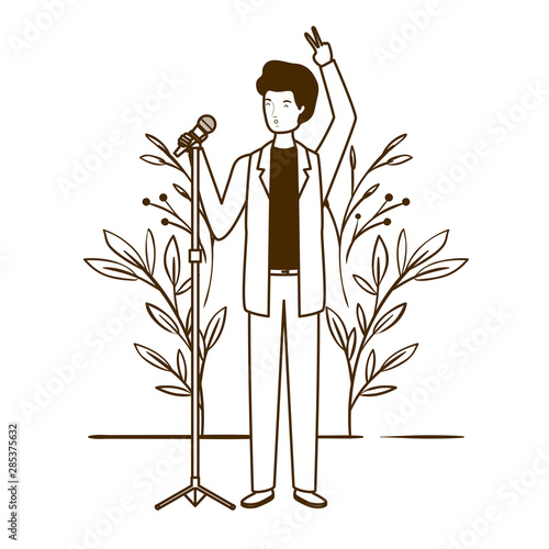 silhouette of man with microphone and branches and leaves in the background photo