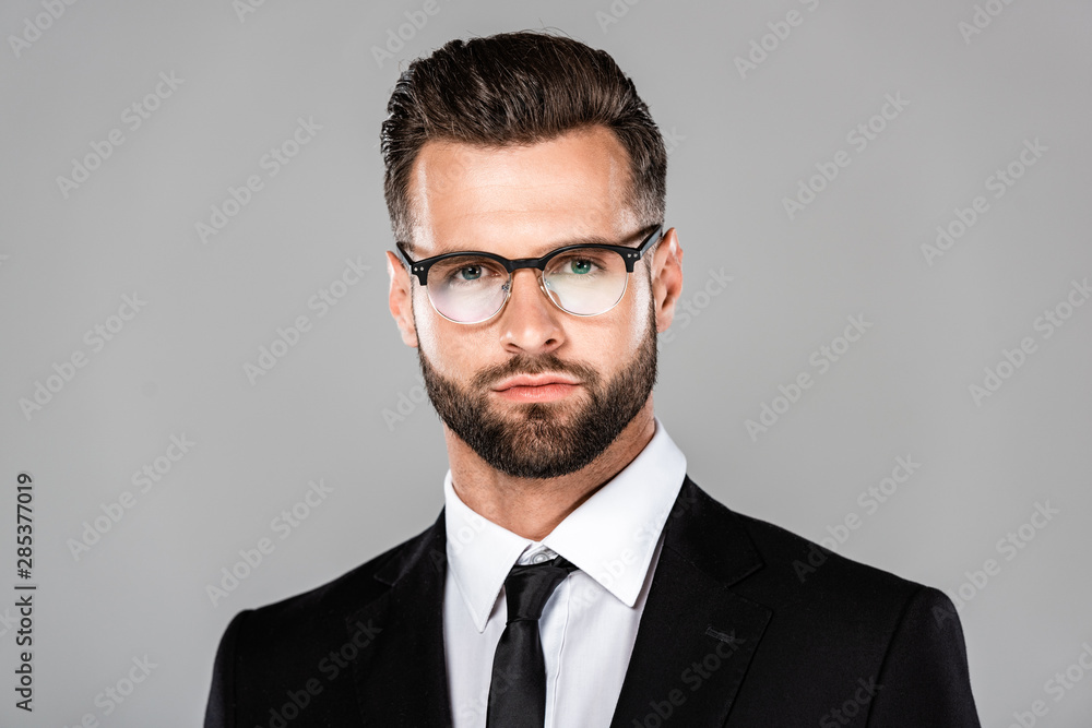 portrait of successful businessman in black suit and glasses isolated on grey portrait of successful businessman in black suit and glasses isolated on grey