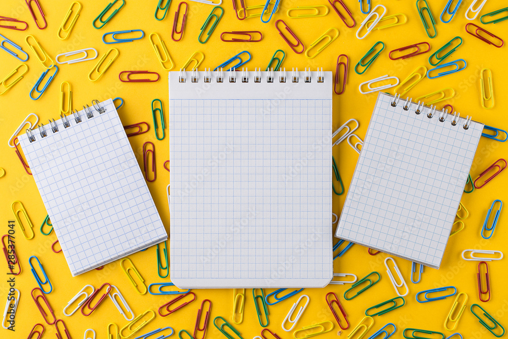 Paper clips and Notepad on bright yellow paper background. Paper clips and Notepad on bright yellow paper background.